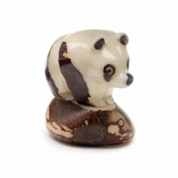 a carving of a panda sitting on top of a tagua seed