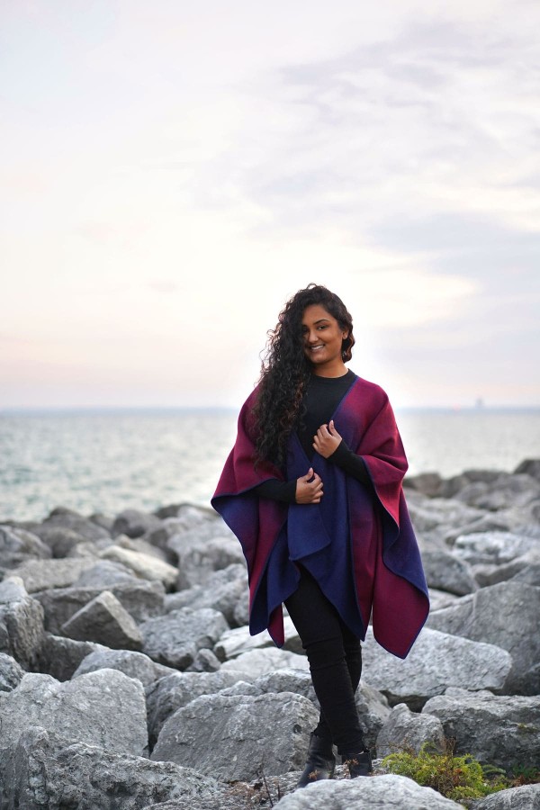 A young women wearing the ombre alpaca cape, this product is made out of 50% alpaca and 50% acrylic