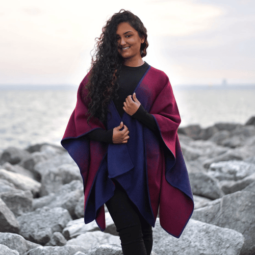 A young women wearing the ombre alpaca cape, this product is made out of 50% alpaca and 50% acrylic