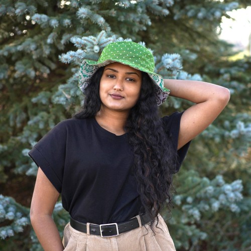 A young women wearing a green bucket hat with with white poke-a-dots on it