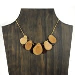 A picture with nine slices of tagua arranged on the necklace, comes in a verity of colors the color in this picture is brown, and white.