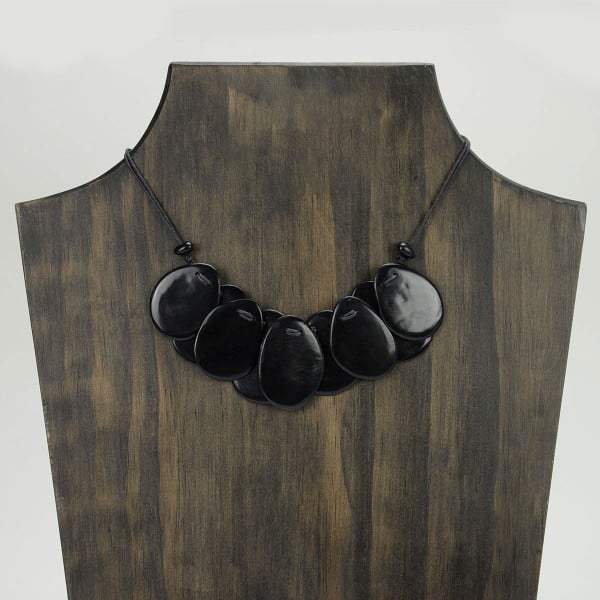 A picture with nine slices of tagua arranged on the necklace, comes in a verity of colors the color in this picture is black.