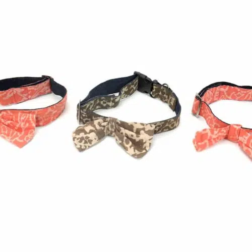 Three dog collars two of them are pink with a coral design on them, and one is brown that has a camo print